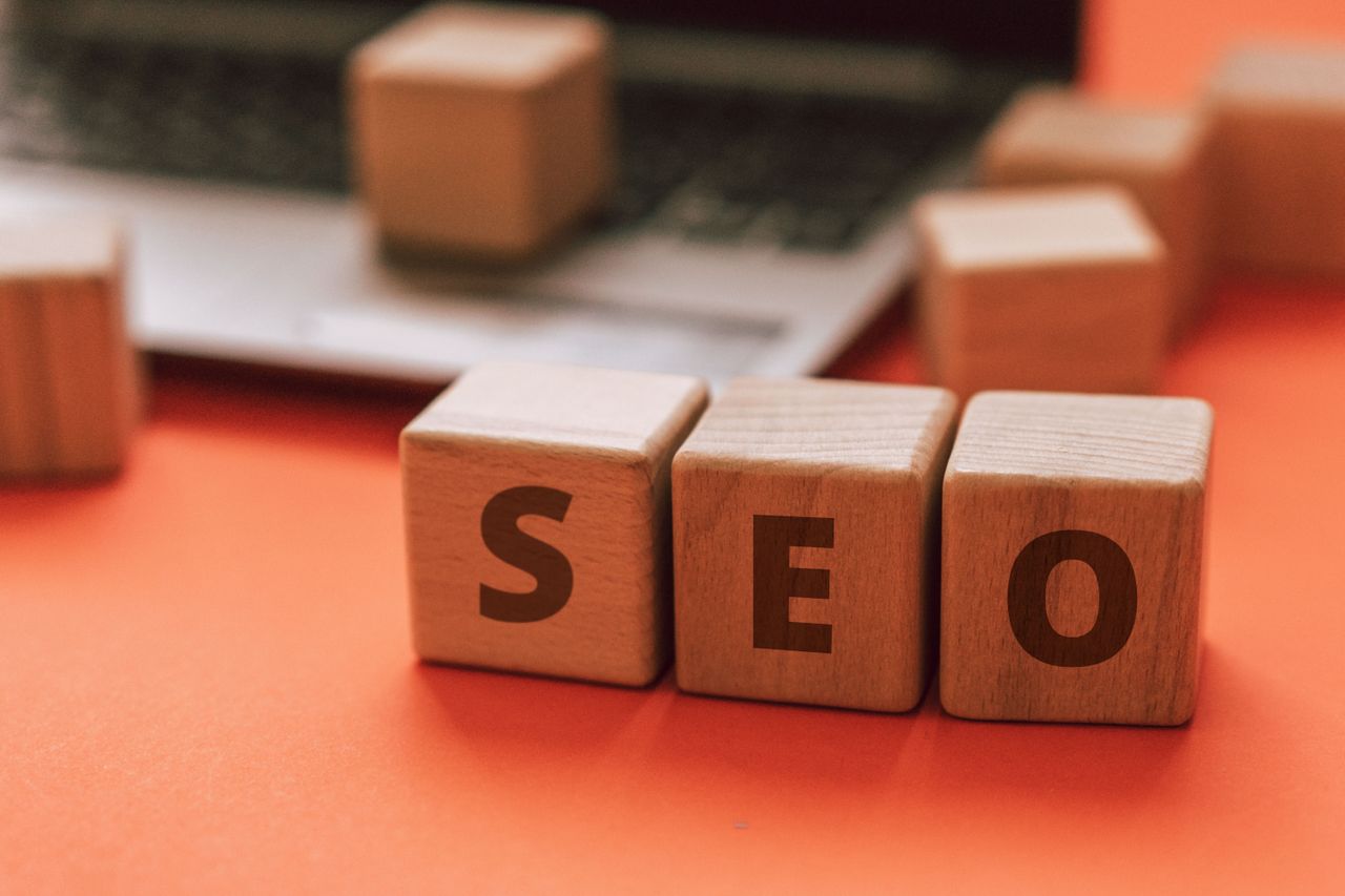 contact-img Wooden blocks spelling SEO on a laptop keyboard convey digital marketing concepts.