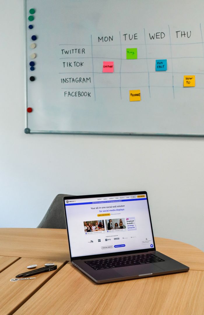 home-services-01 A modern office setup featuring a laptop and a whiteboard schedule for social media platforms.